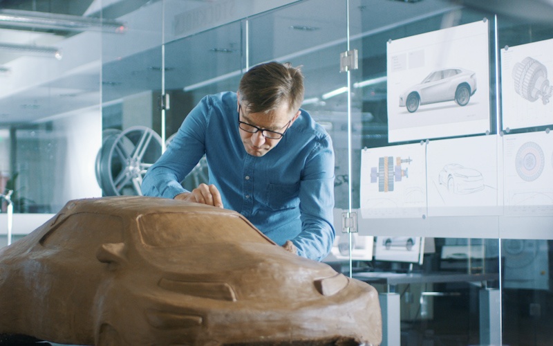 experience automotive designer with a rake sculpts prototype car model from plasticine clay