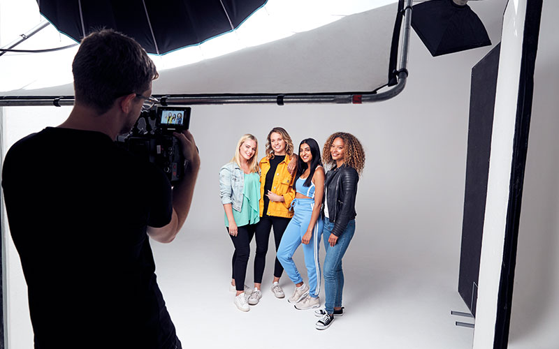 couple; group; friends; model; modeling; photography; film; set; shooting; photo session; women; woman; female; happy; smiling; laughing; laughter; joy; happiness; positive; confident; emotions; expression; fun; together; studio; white background; front view; person; people; 20s; twenties; caucasian; mixed race; mauritian; african american; multi-cultural; casual clothing; fashion; portrait; looking at camera; hanging out; copy space; support; supportive; mates; horizontal; photographer; cameraman