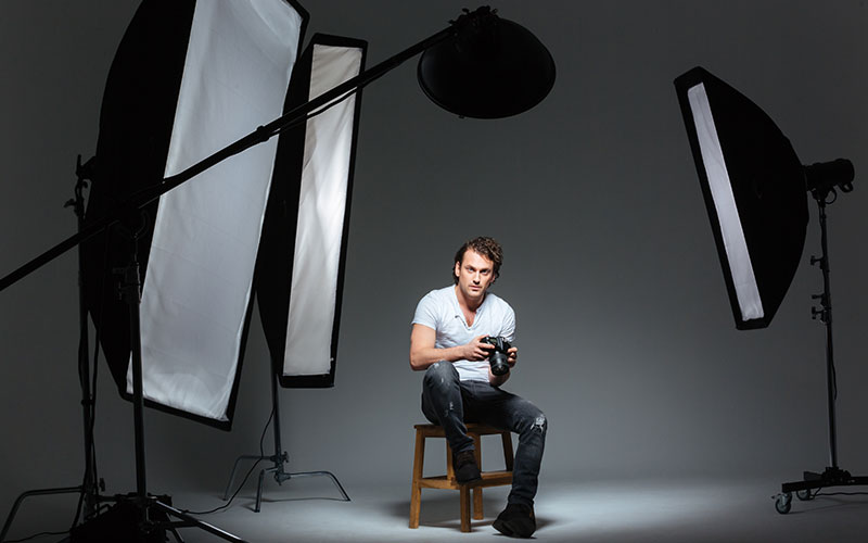 Man photograph sitting on the chair in studio with camera