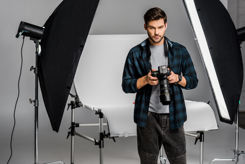 Man photograph sitting on the chair in studio with camera